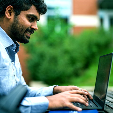 UNH student working on laptop outside