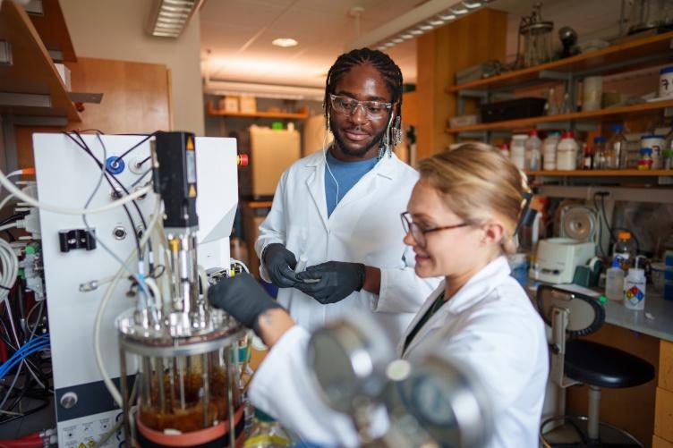 Two students work in a lab using advanced instrumentation.